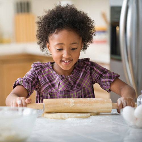 Mixed race girl rolling out dough