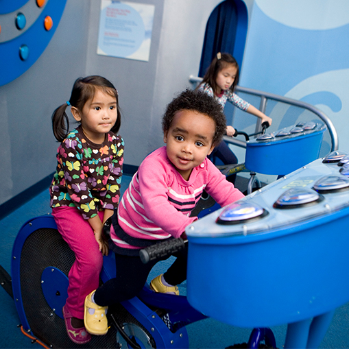 female children in blue room pretending to ride bicycles