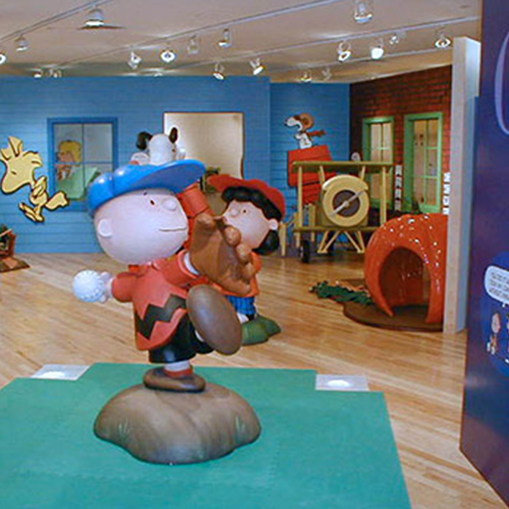 museum exhibit with charlie brown throwing a baseball and lucy behind him from peanuts