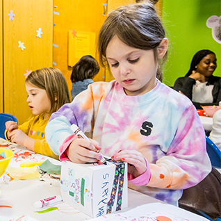 girls making art with adult in the background