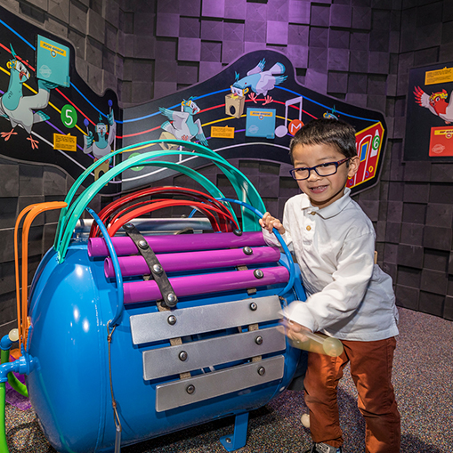 child with glasses playing a circular xylophone