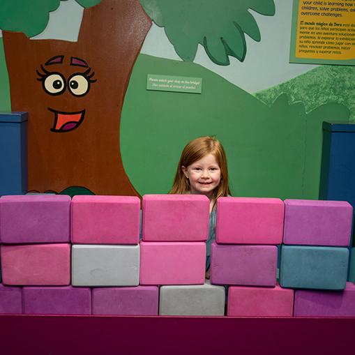 little girl hiding behind a pink wall