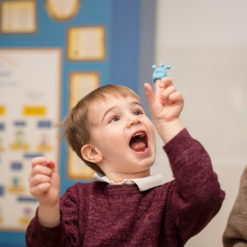 little boy holding up his finger excitedly with a finger puppet on it