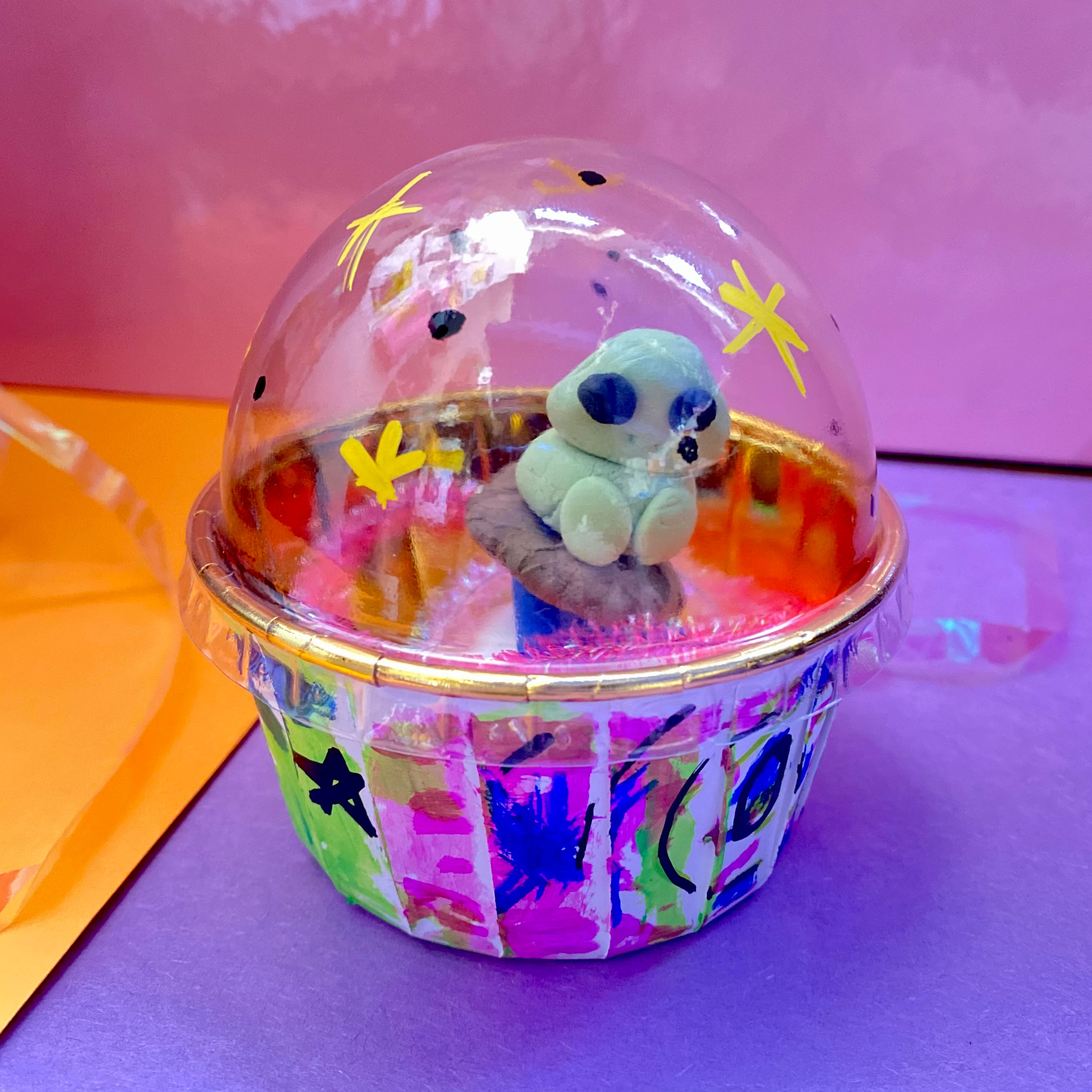 an art project of a little alien in a ufo that is actually a takeout cup