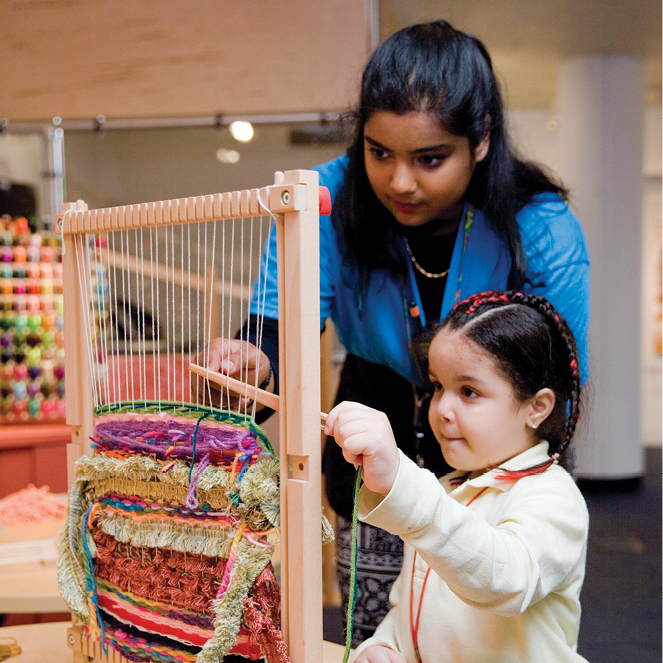 A CMOM educator and child create a colorful weaving together in the Inside Art exhibit.