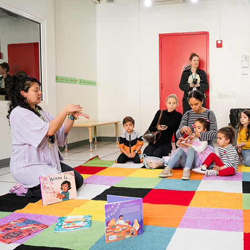 woman demonstrating art to children sitting on floor