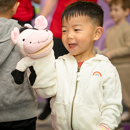 little boy smiling and hold a cow puppet