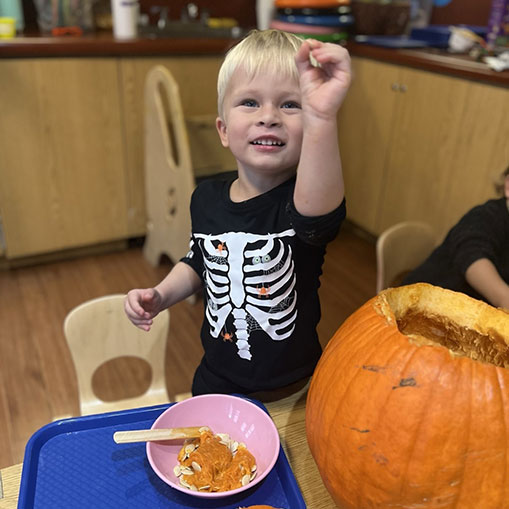 little boy playing with a pumpkin