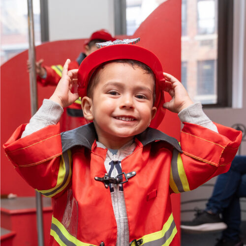 A boy dressed up as a firefighter plays in the PlayWorks exhibit.