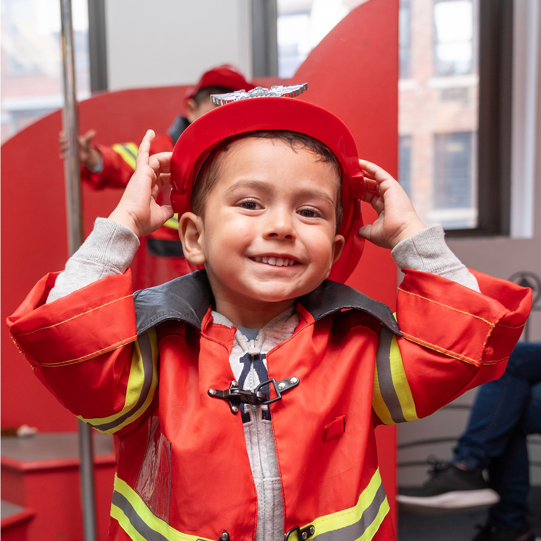 A boy dressed up as a firefighter plays in the PlayWorks exhibit.
