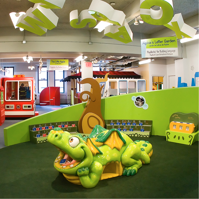 The photo shows an image of Alphie, CMOM's green talking dragon in the exhibit PlayWorks.