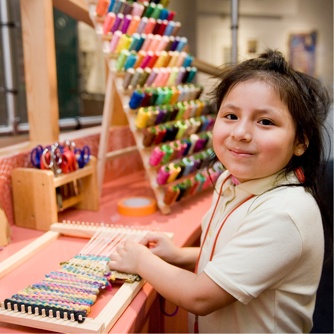 A girl works on a colorful weaving in the Inside Art exhibit.