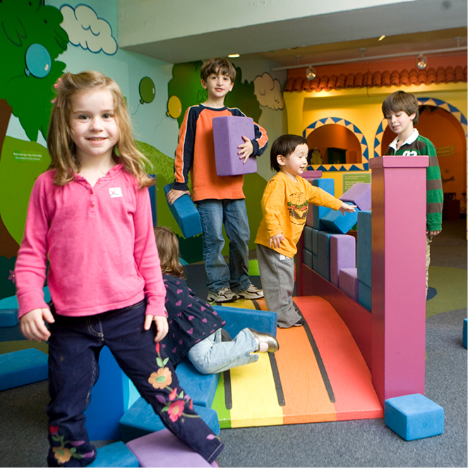Kids play on a rainbow bridge in the Dora and Diego exhibit.