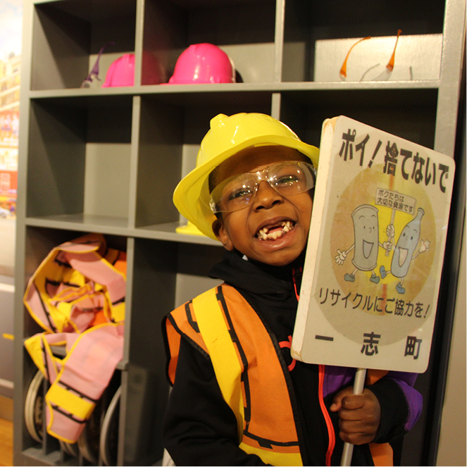A boy happily holds a sign as he plays in the Hello from Japan exhibit.