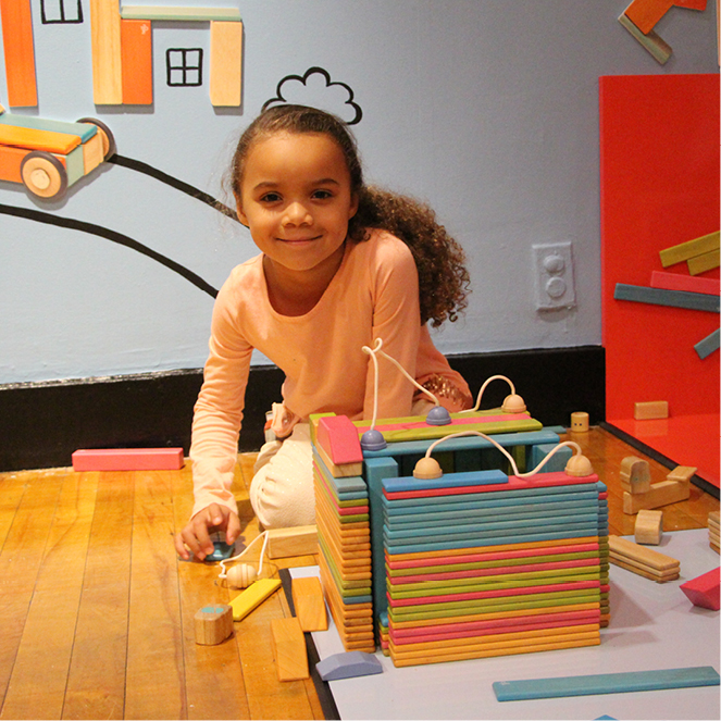 A girl builds with colorful blocks in the Building Wonderlands exhibit.