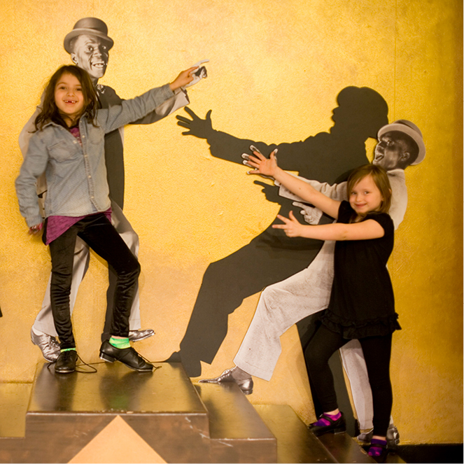 Two girls pose with tap shoes in the Jazzed exhibit.