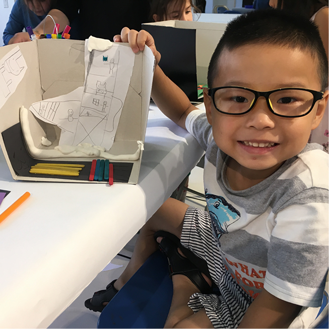 Boy with glasses creating a building.