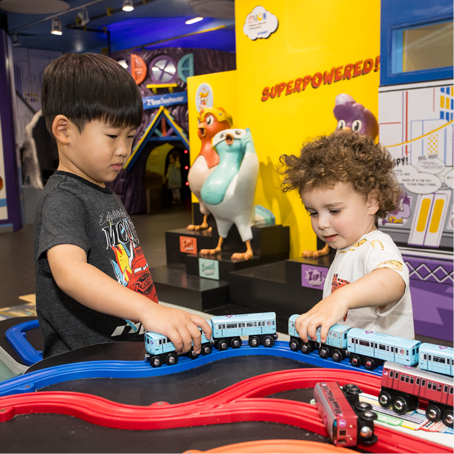 Two kids play with trains at the train table in CMOM Superpowered Metropolis exhibit.