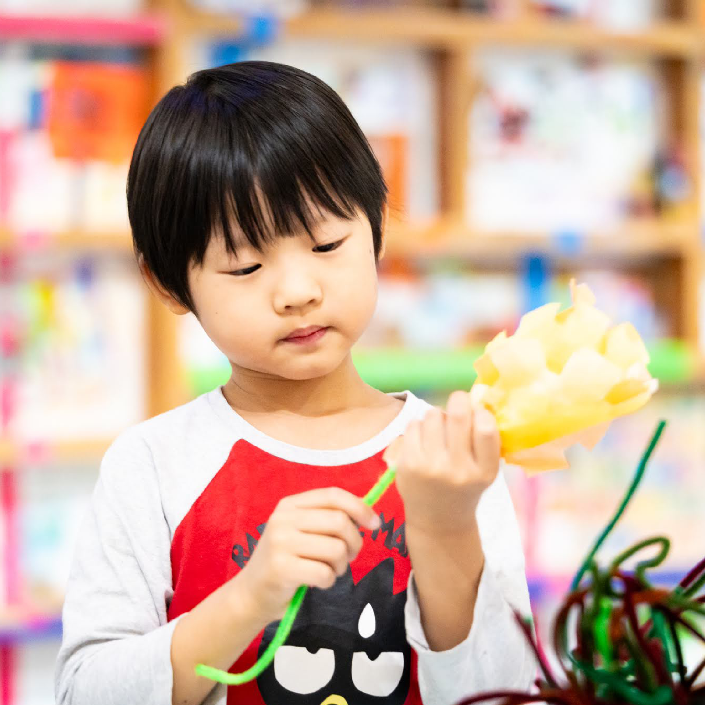 A child makes an orange flower out of tissue paper.