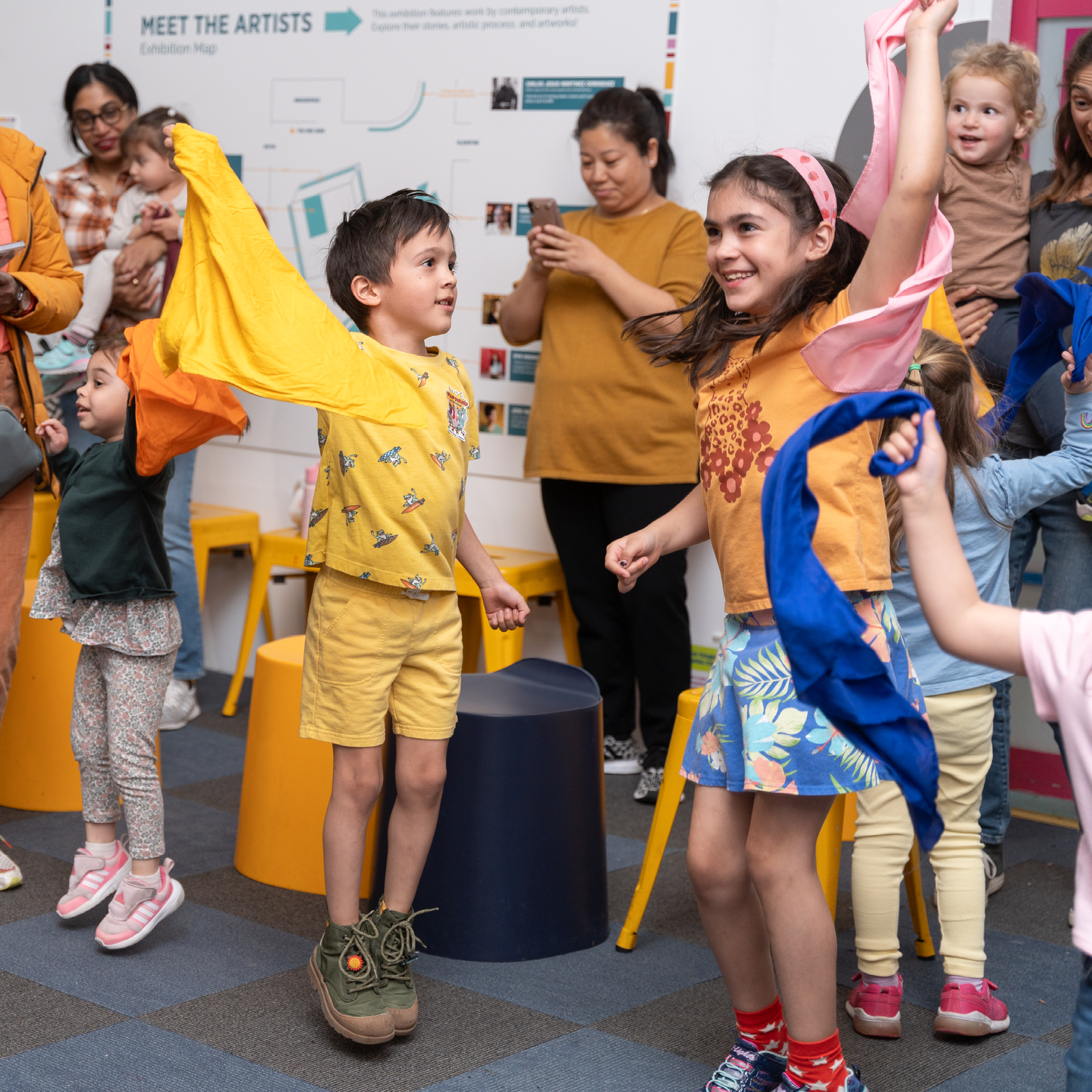 Kids dance and wave scarves during a performance