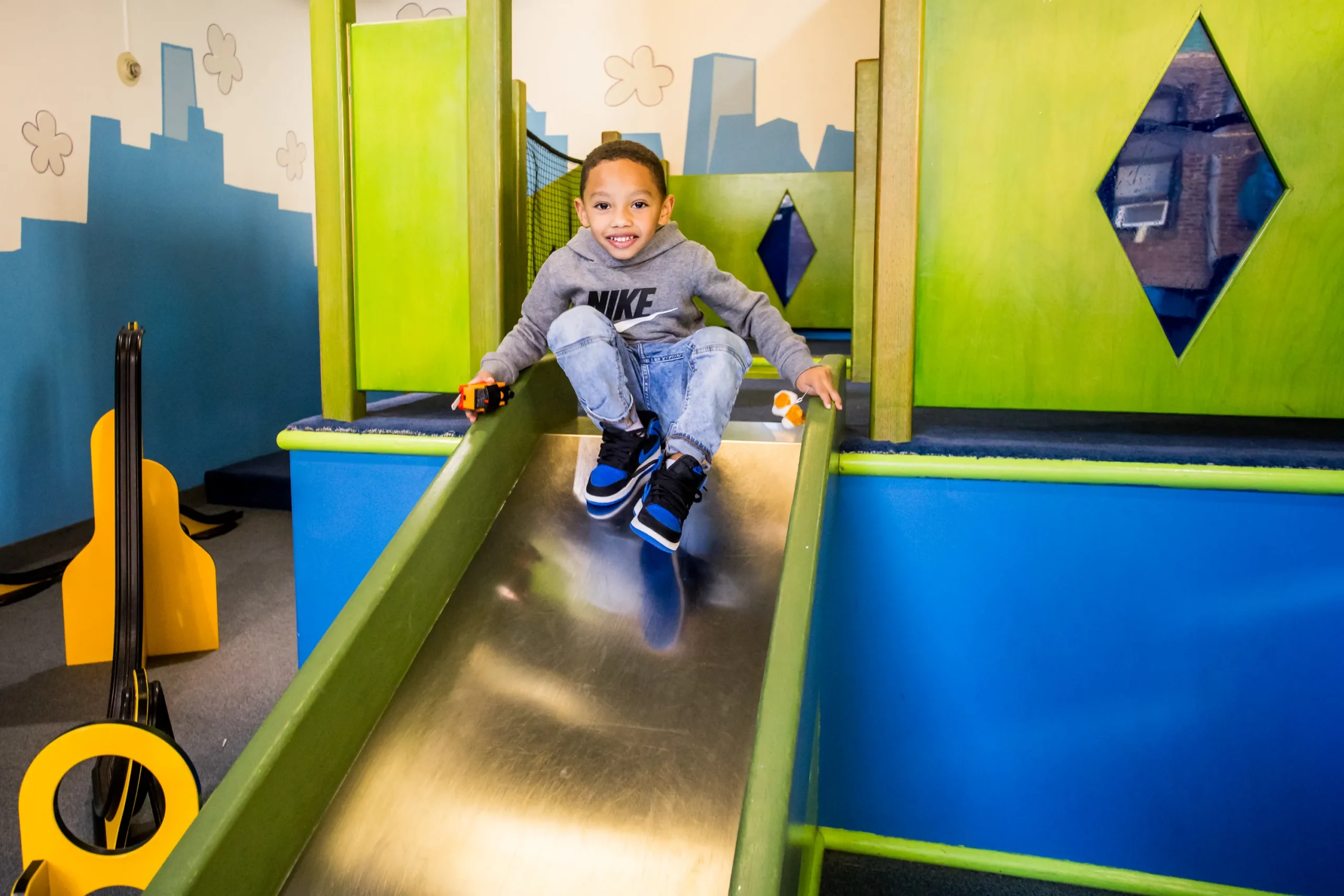 A young child sits at the top of the slide, prepared to slide down