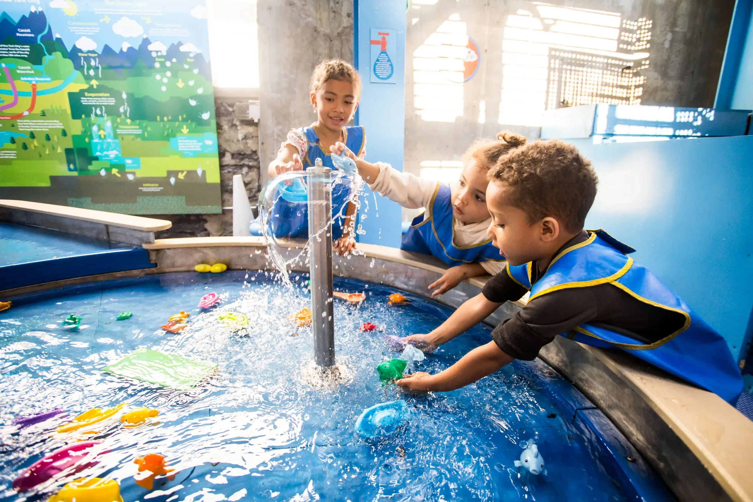 Three young children play at a water table
