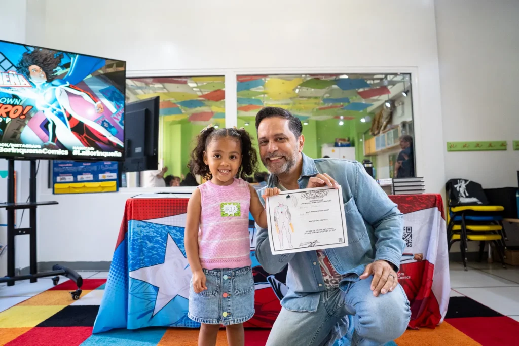 A young child and adult man both hold a certificate that says "Superhero!"