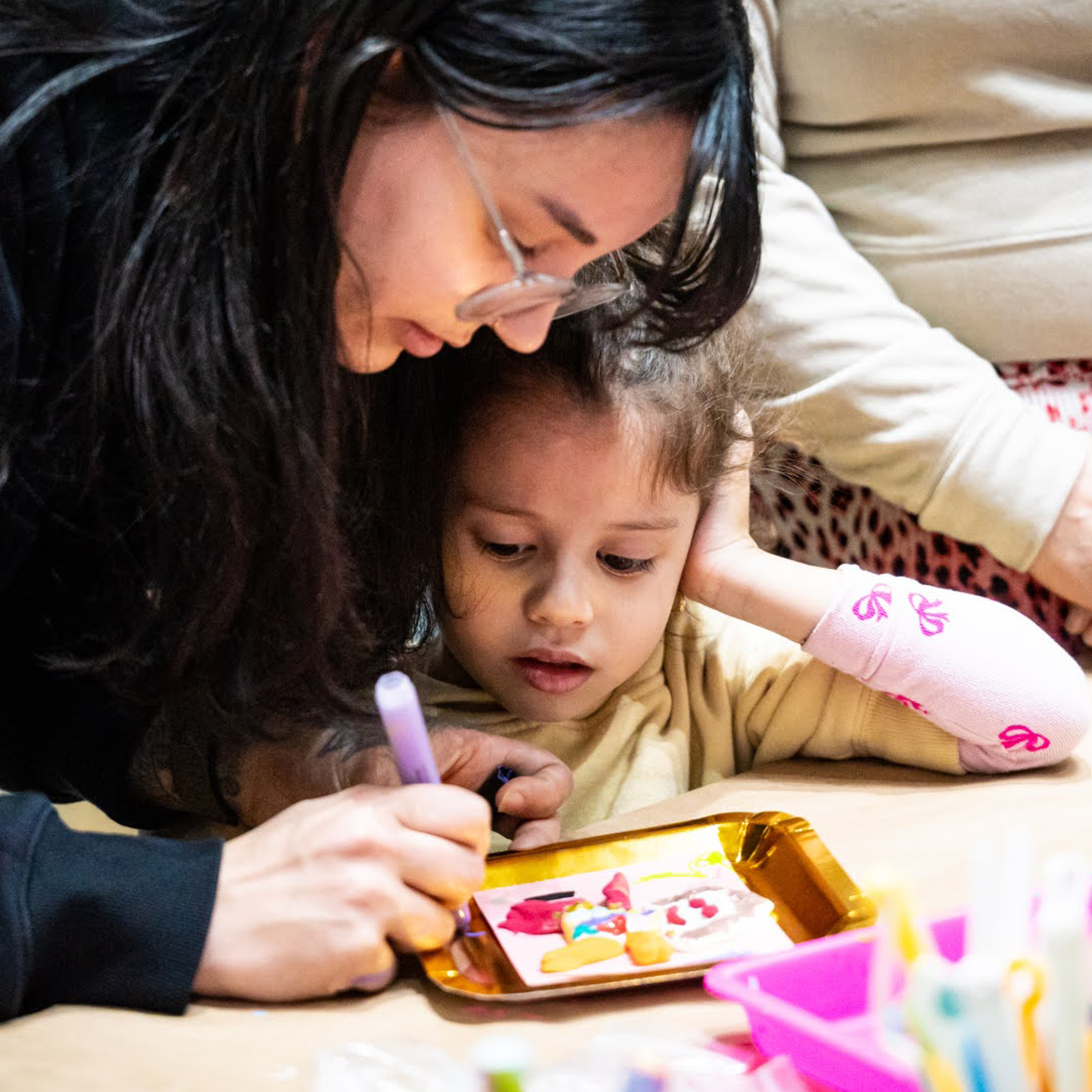 Child and parent work on a clay portrait together.