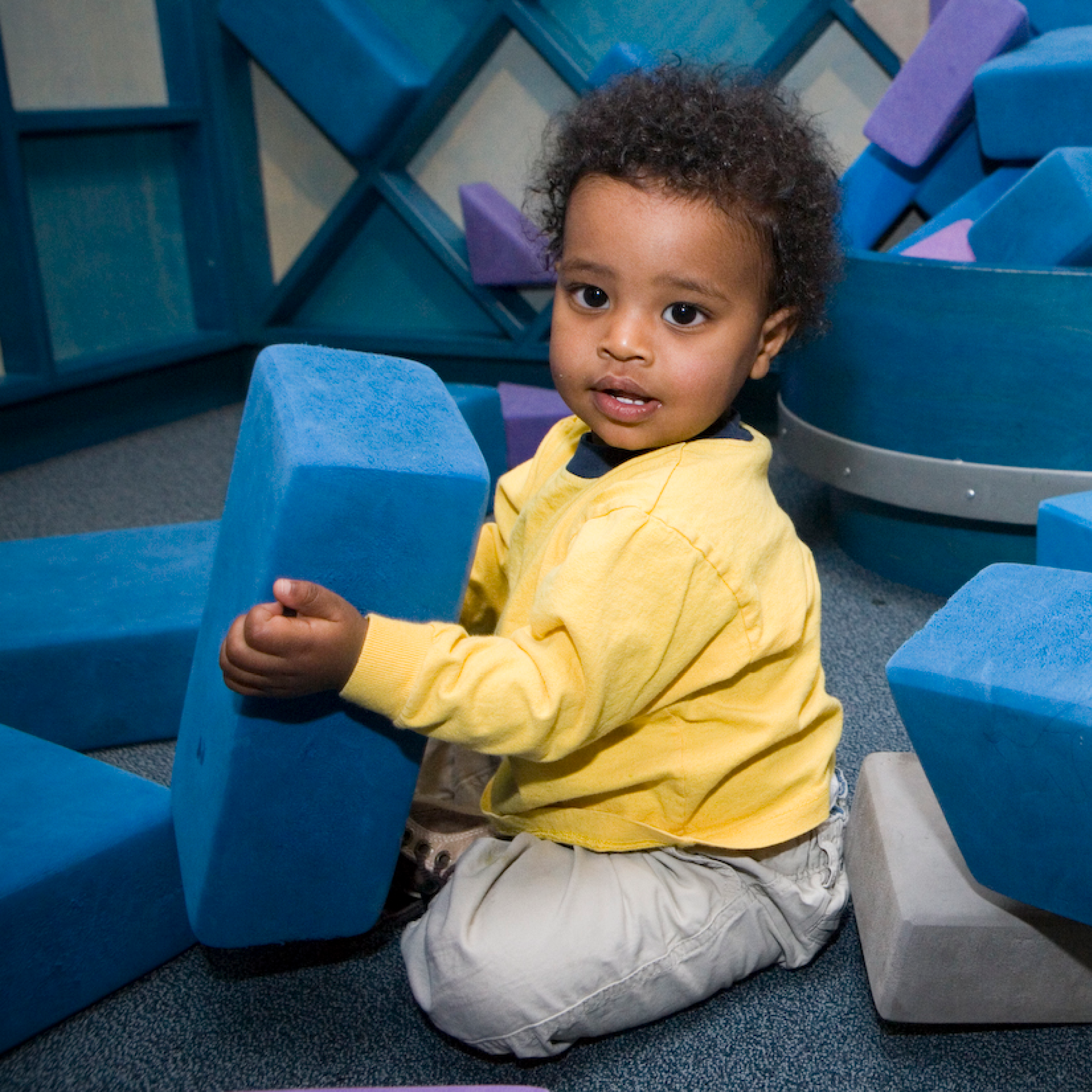 Baby sits and holds a foam block.