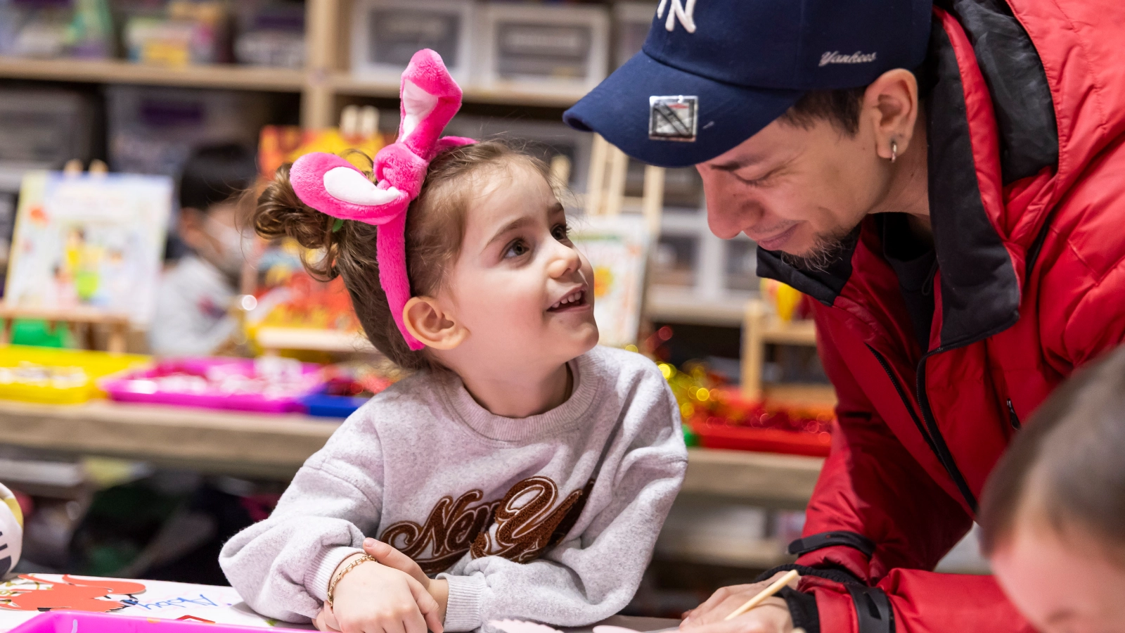 A young, pre-school aged girl smiling at an adult man.