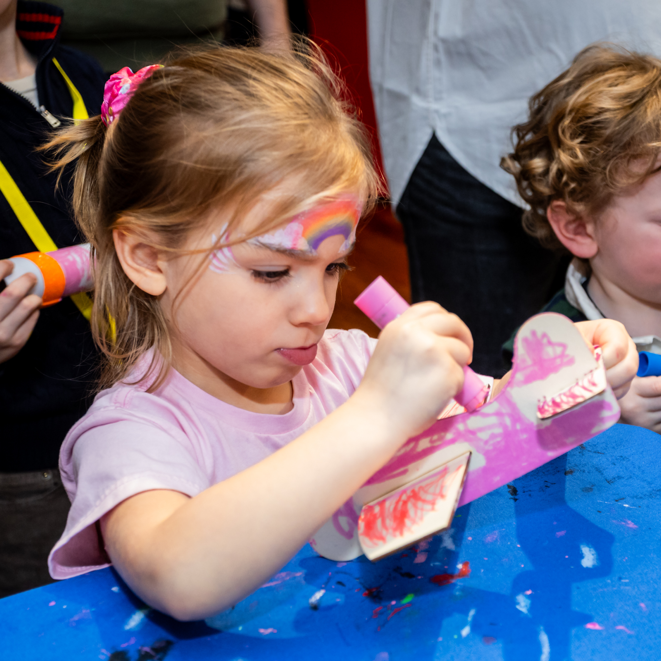 Child colors a wooden airplane pink