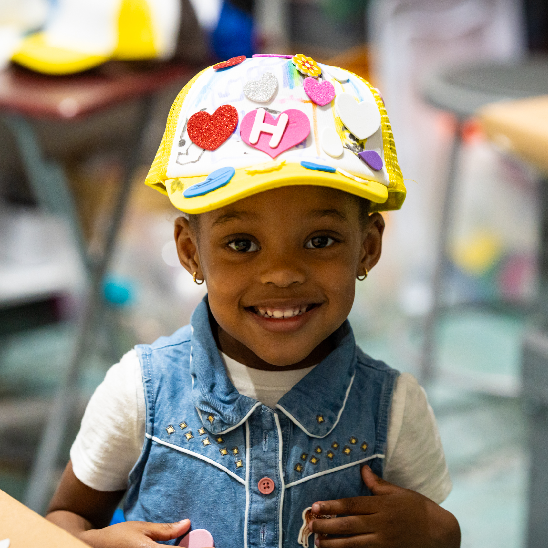 Child happily wears a hat they made.