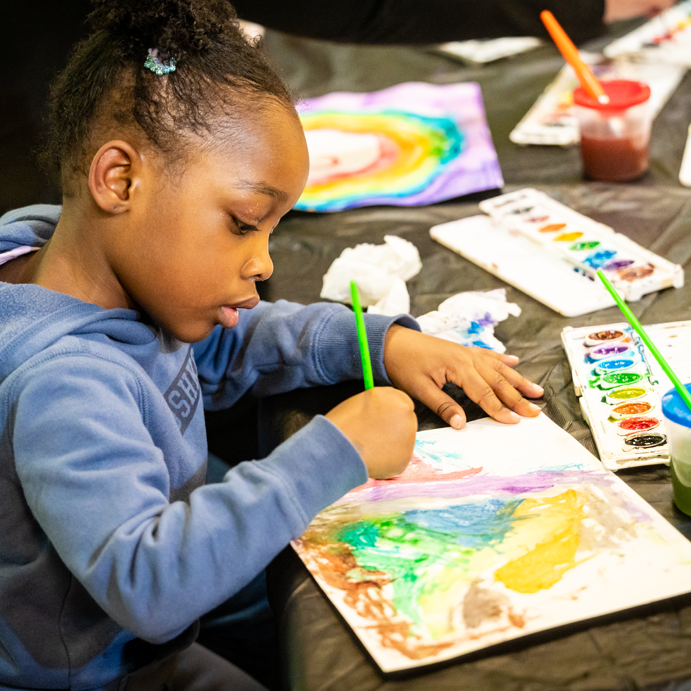 Child paints a watercolor scene of a landscape.