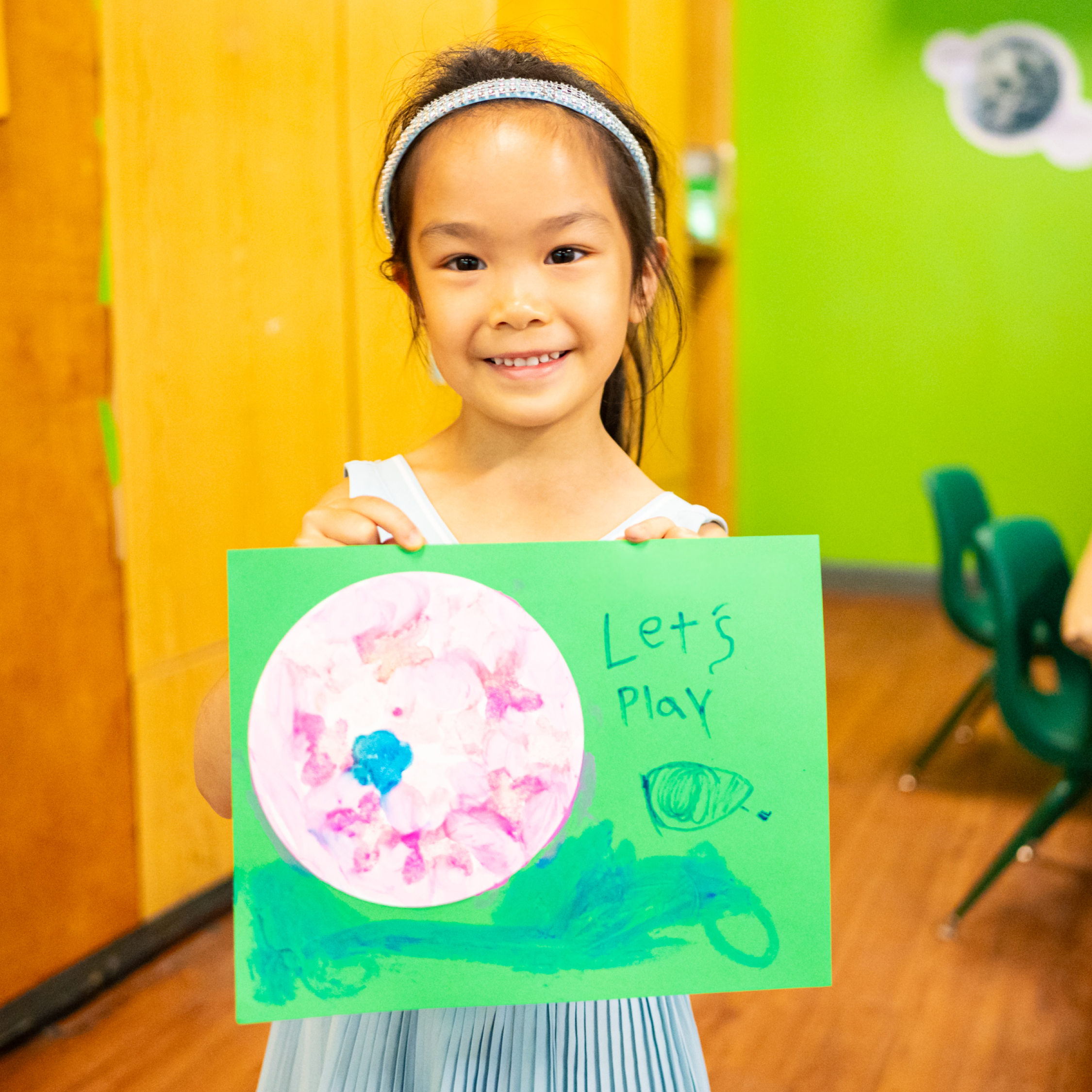 Child holds up their summery artwork.