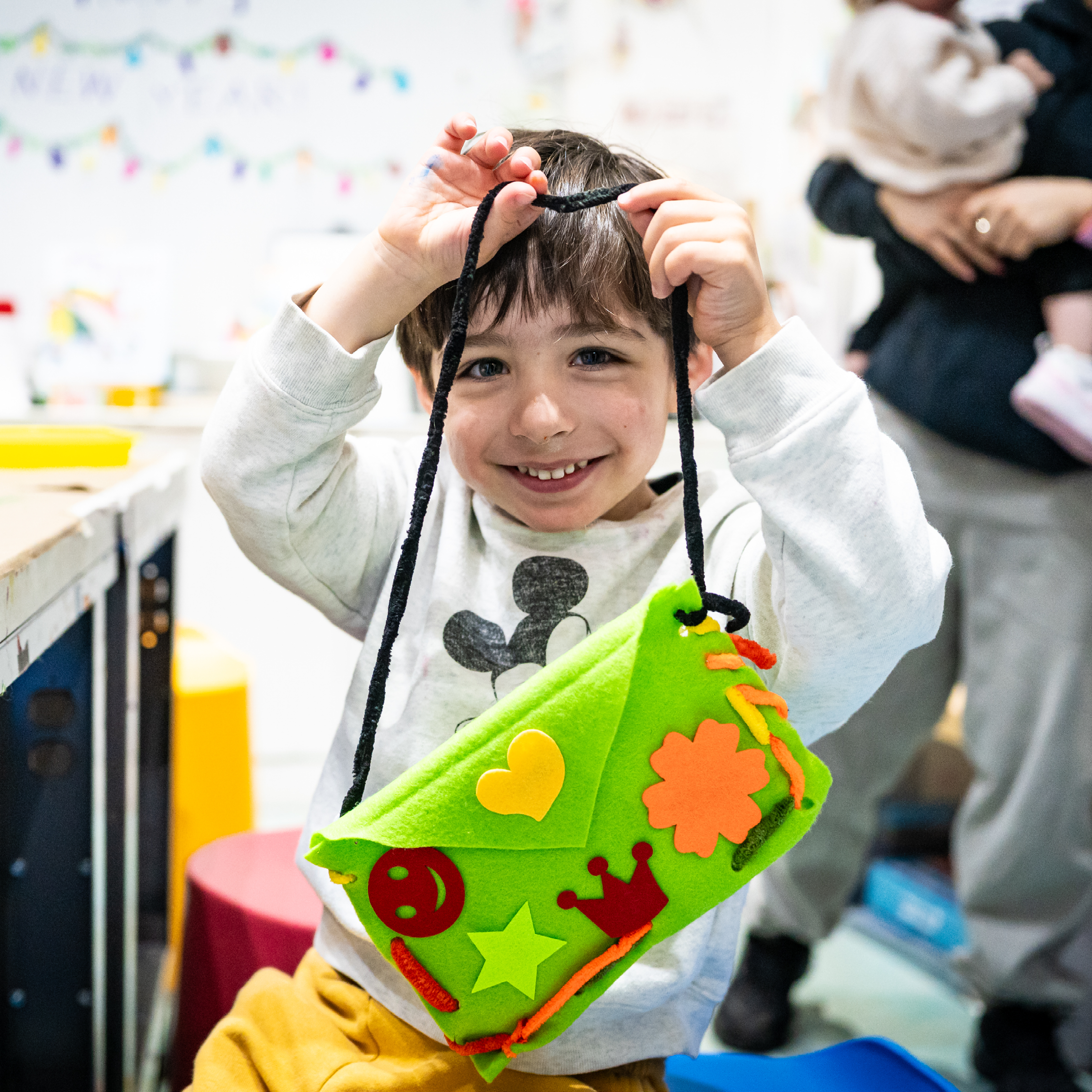 Child holds up a handmade green pouch