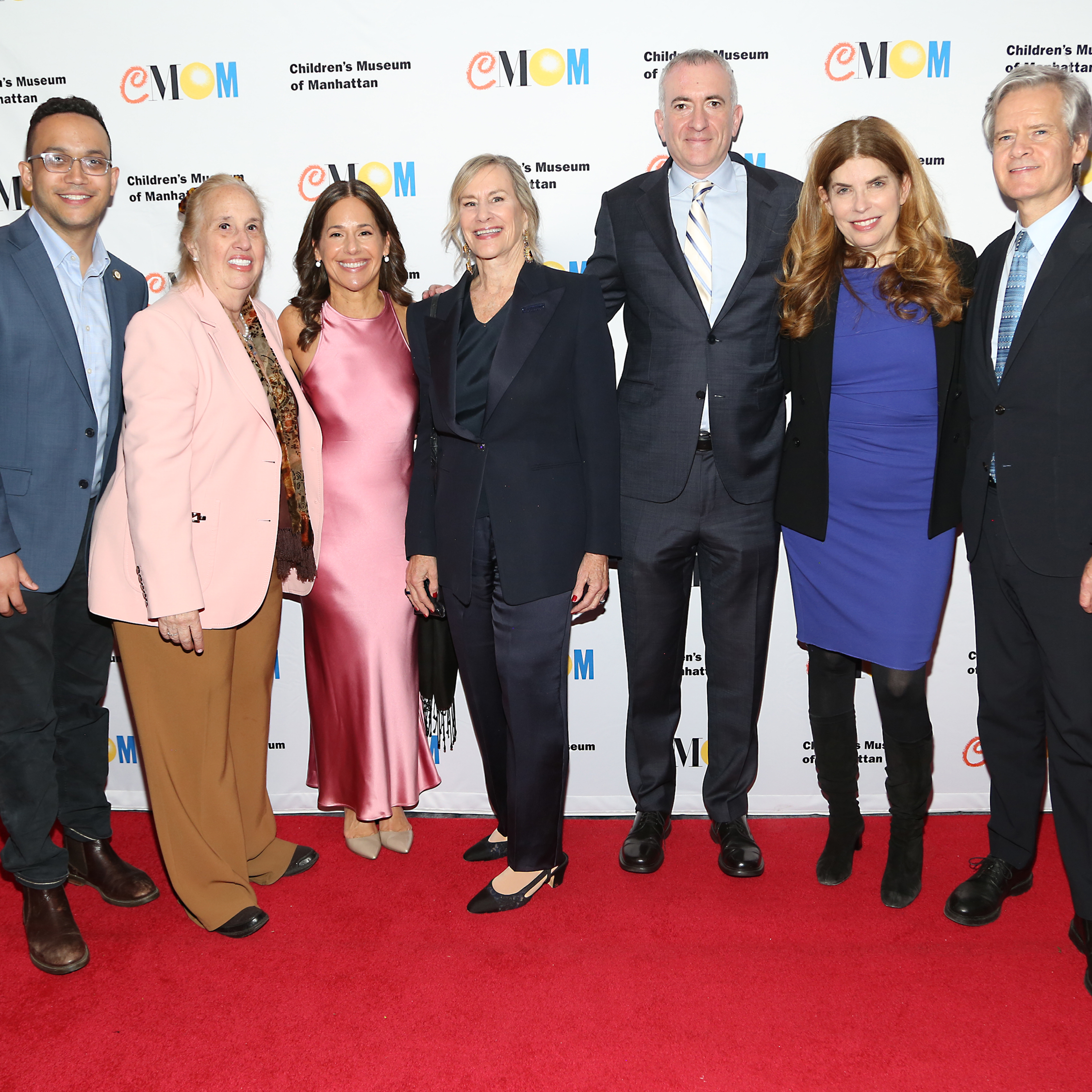 A group stands for a photo in front CMOM's step and repeat at the Annual Gala