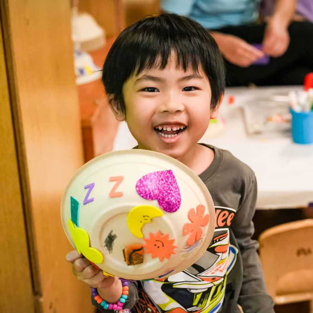 Child holds up a collage sun they made