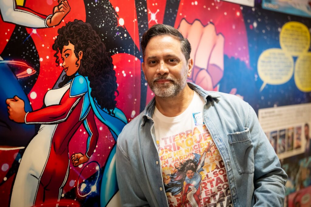 Man smiles next to comic book art.