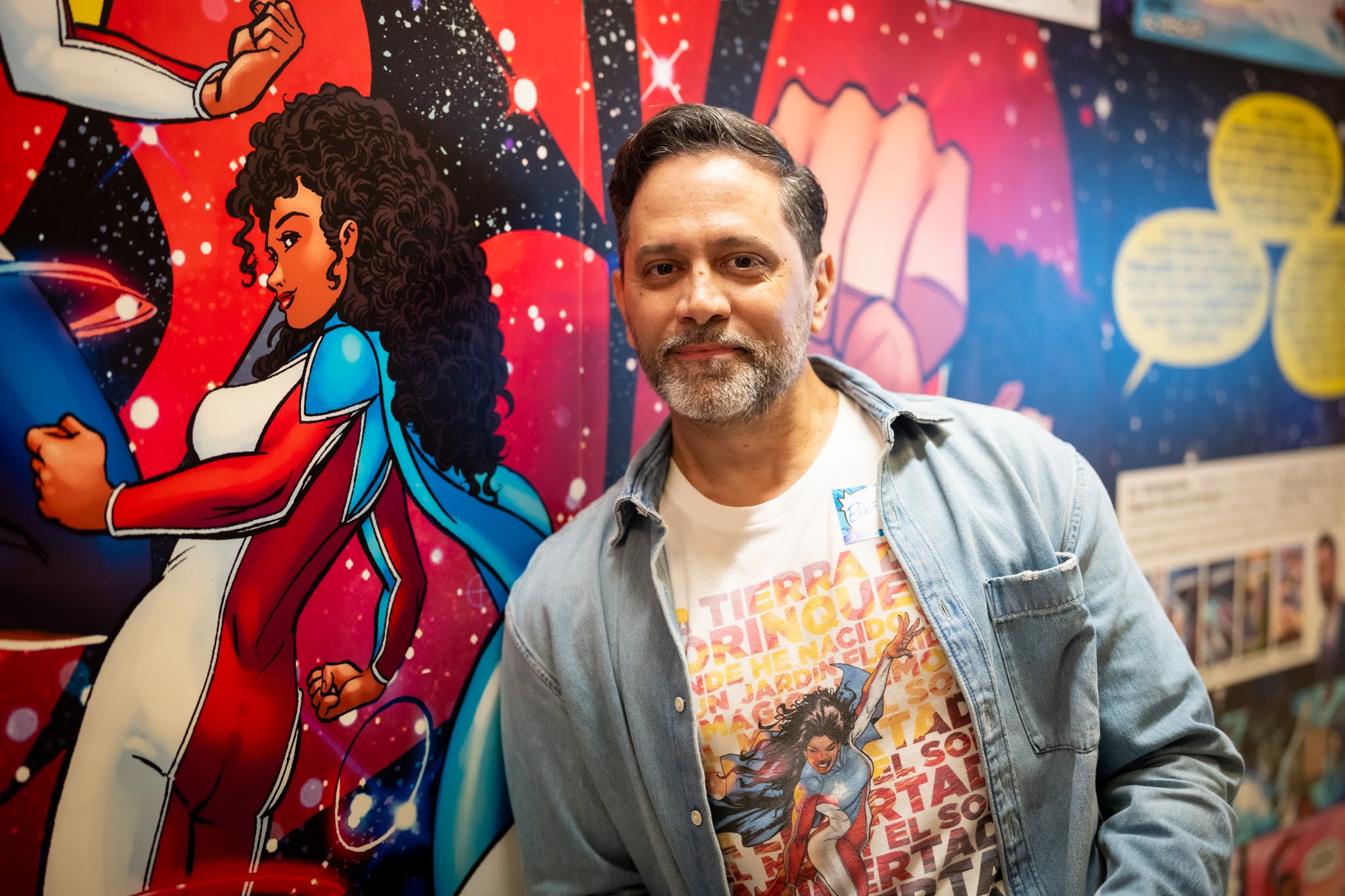 Man smiles next to comic book art.