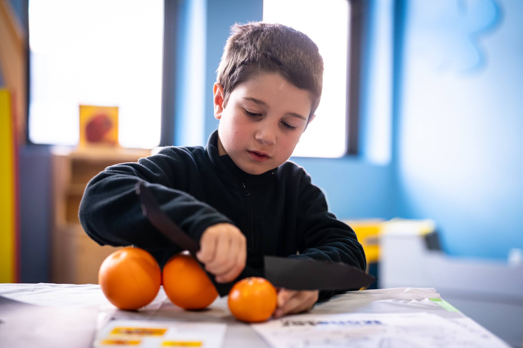 A child plays with oranges in front o f him. Children's Museum Of Manhattan photos by @StewPhotographyNYC