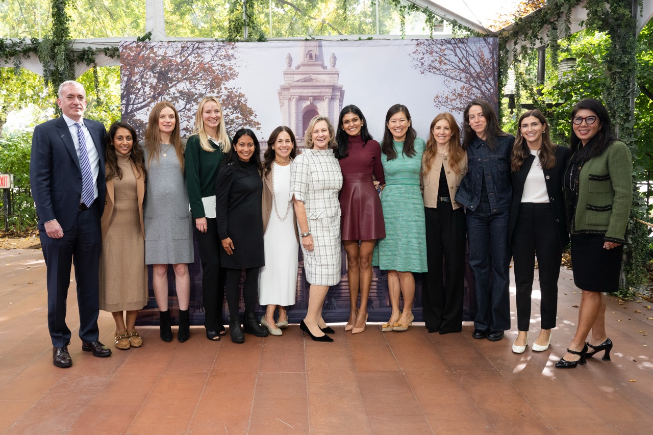 Thirteen adults smiles at the camera while standing in a line