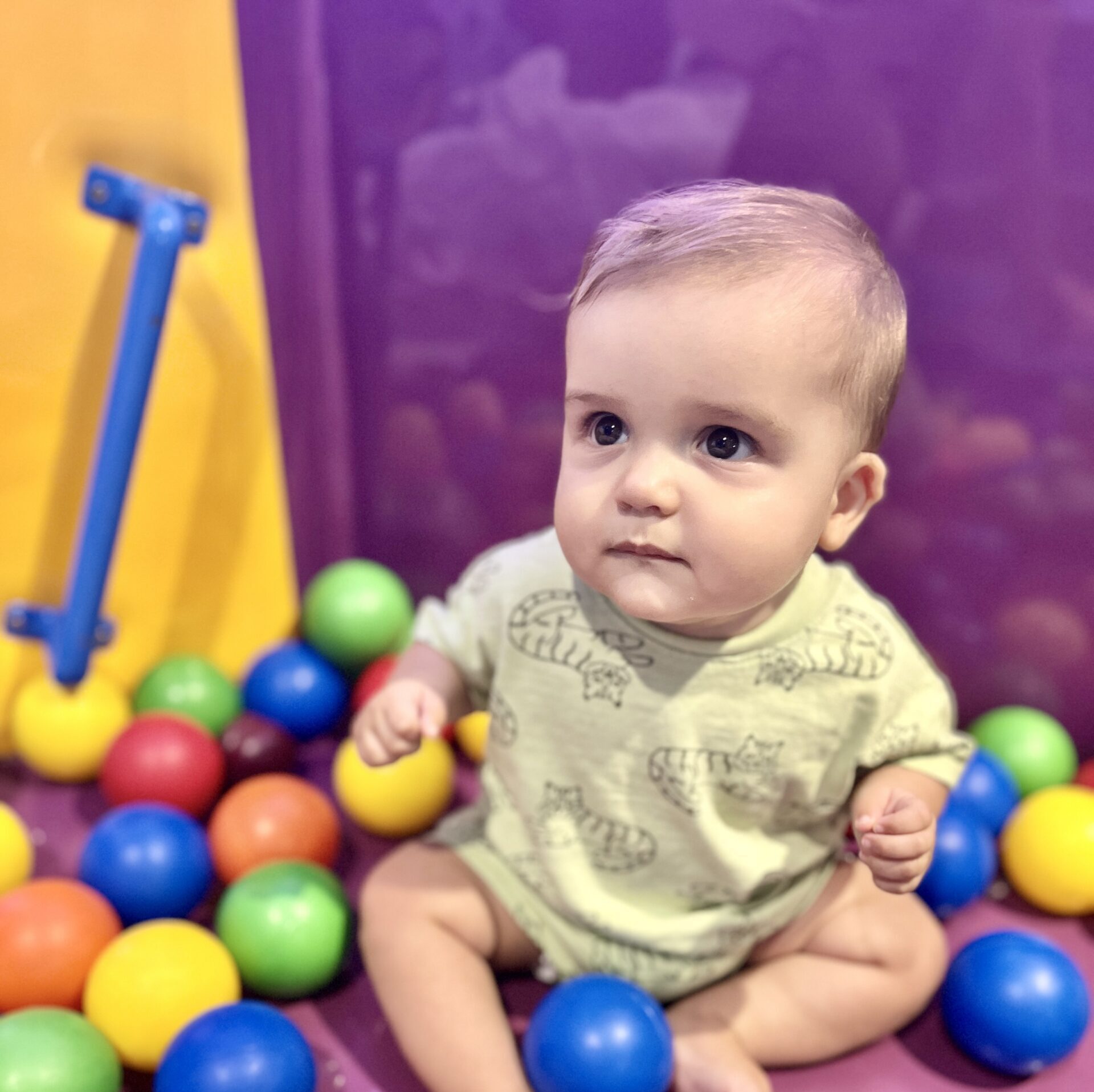 Infant sits among play toy multicolor balls