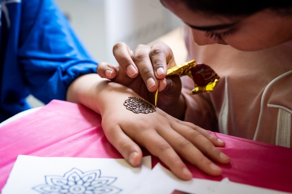 A close-up of henna being applied to a child's hand.