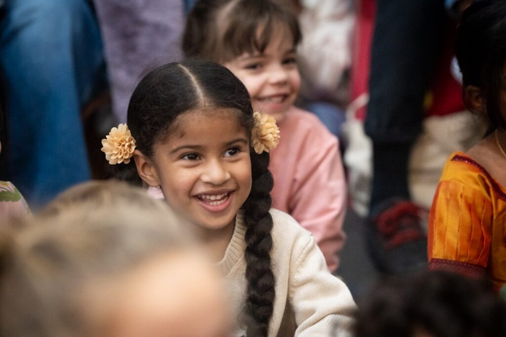 Children smile while watching something off-camera.