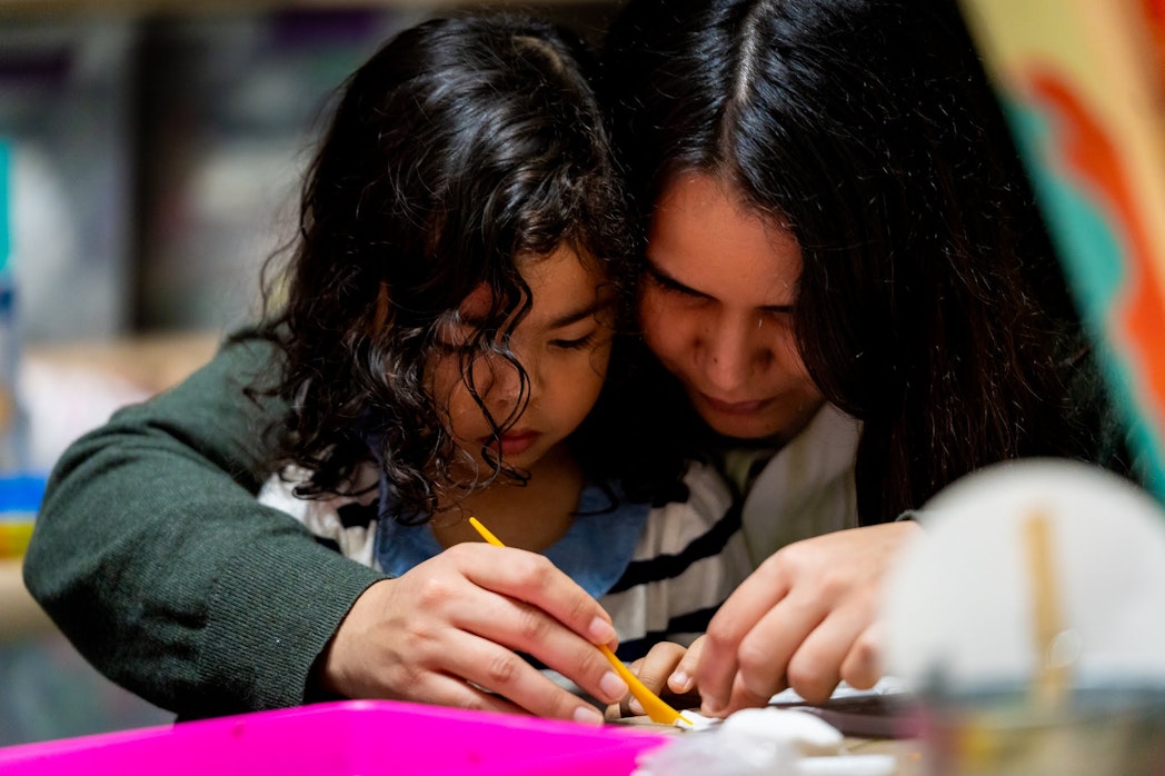 An adult helps a young child paint with a small brush at the Children’s Museum of Manhattan.
